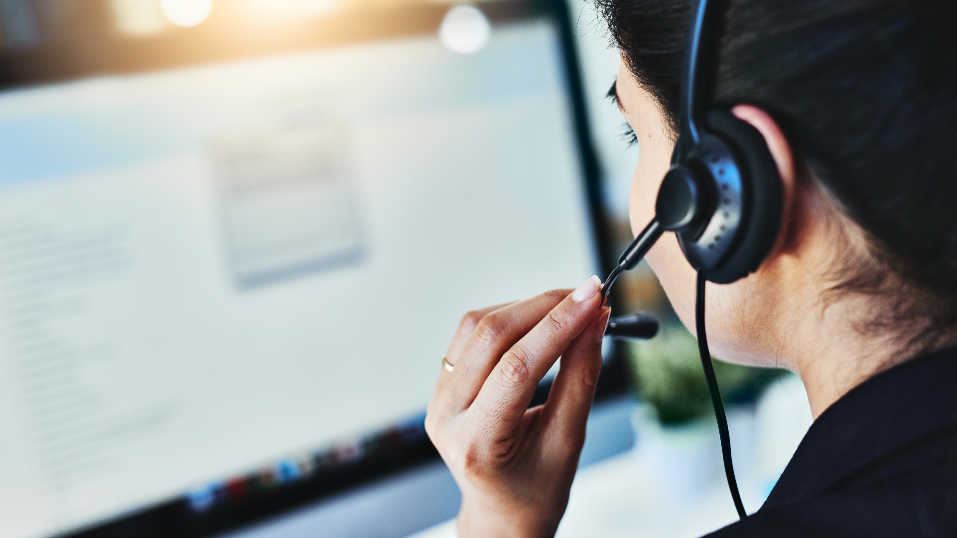 Customer support agent wearing a headset and working on a computer to deliver exceptional customer experience in a modern contact center.