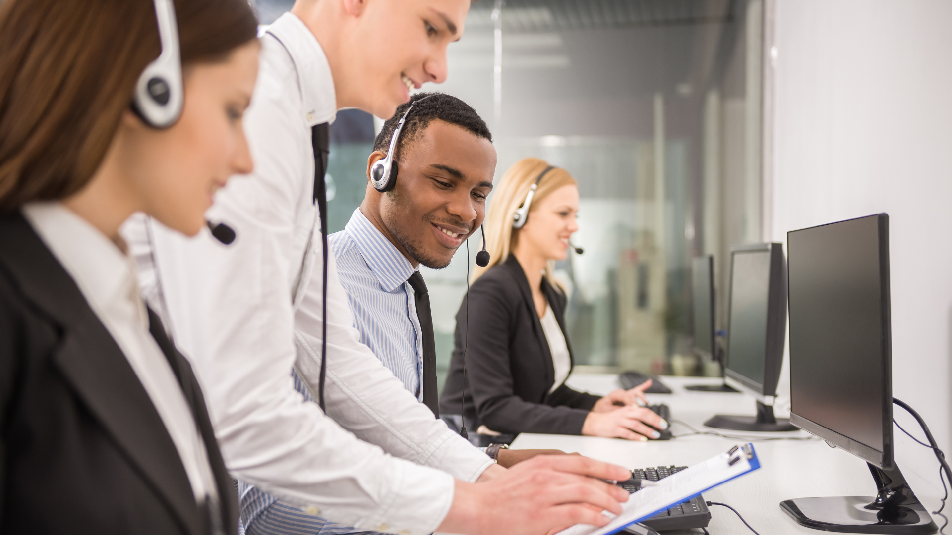 Diverse contact center agents wearing headsets working together in a modern office, providing customer support.